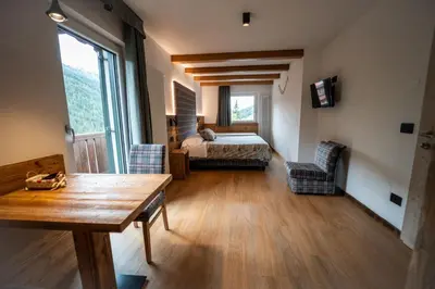 a room with a bedroom with a bed and a table at B&B Bucaneve in Vigo di Fassa