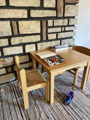 a wooden table and a chair and a brick wall at B&B Bucaneve in Vigo di Fassa