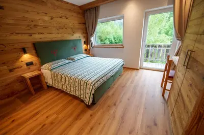 a bedroom with a bed and a wooden floor at B&B Bucaneve in Vigo di Fassa