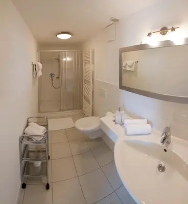 a white bathroom with a sink and a toilet at Appartementhaus Linter in Tirolo