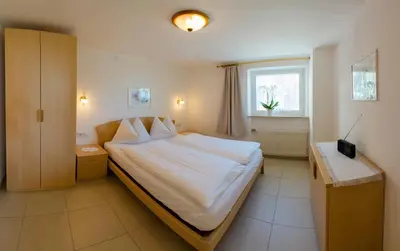 a bedroom with a large bed and a window at Appartementhaus Linter in Tirolo