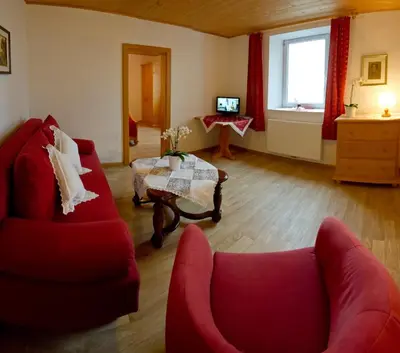 a living room with two red chairs and a table at Appartementhaus Linter in Tirolo