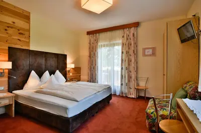a bedroom with a large bed and a large window at Hotel Villnerhof in Egna