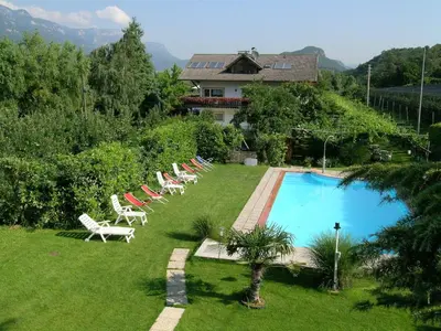 a group of lawn chairs and a swimming pool at Hotel Villnerhof in Egna