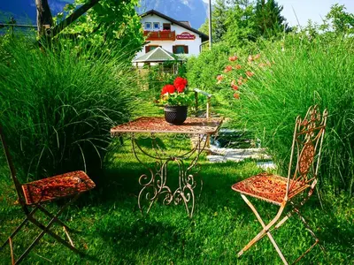 a table and two chairs in a yard with plants at Hotel Villnerhof in Egna