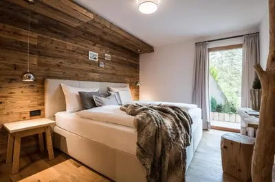 a bedroom with wooden walls and a large bed at Les Dolomites Mountain Lodges in San Martino in Badia