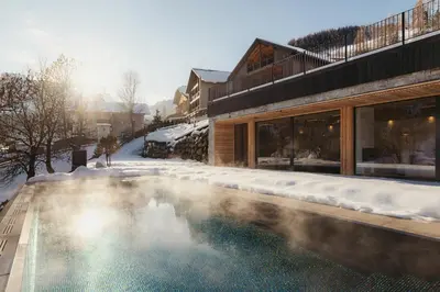 a living room with white furniture and a fireplace at Les Dolomites Mountain Lodges in San Martino in Badia