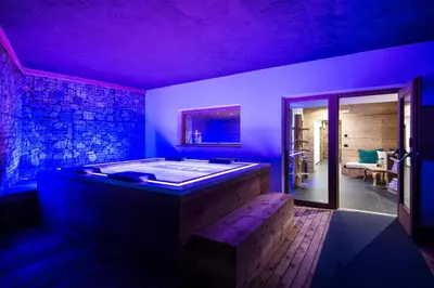 a jacuzzi tub in a room with chairs at Les Dolomites Mountain Lodges in San Martino in Badia