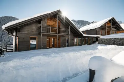 a house in the snow with snow covered roofs at Les Dolomites Mountain Lodges in San Martino in Badia