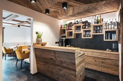 a bar in a restaurant with wooden walls and chairs at Les Dolomites Mountain Lodges in San Martino in Badia