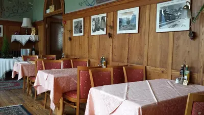 a dining room with tables and chairs with pink table cloth at Hotel Savoia in Canazei