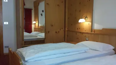 a bedroom with two beds and a large mirror at Hotel Savoia in Canazei