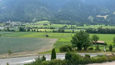 a valley with a road and green fields and mountains at B&B Garni Hotel Saxl in Campo di Trens