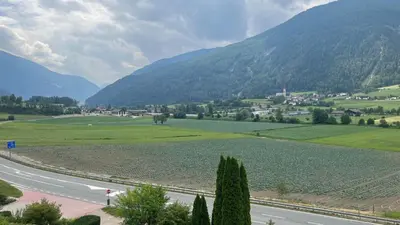 a road in a valley with mountains in the background at B&B Garni Hotel Saxl in Campo di Trens