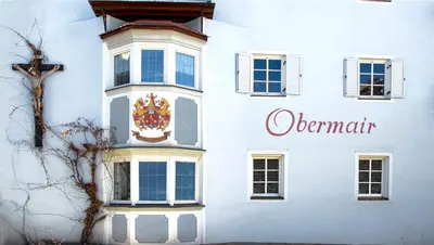 a white building with a clock on the side of it at Gasthof Obermair in Chienes