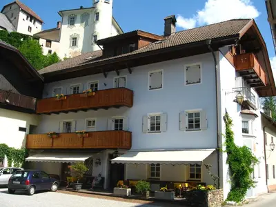 a white building with balconies and a car parked in front at Gasthof Obermair in Chienes