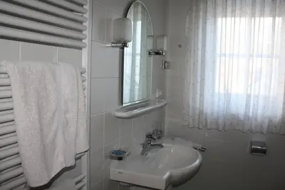 a white bathroom with a sink and a mirror at Gasthof Obermair in Chienes
