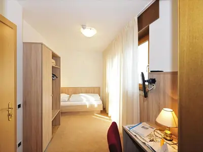 a hotel room with a bed and a desk with a lamp at Hotel-Garni Appartement Gartenheim in Schenna