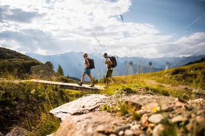 two people walking on a path in the mountains at Hotel-Garni Appartement Gartenheim in Schenna