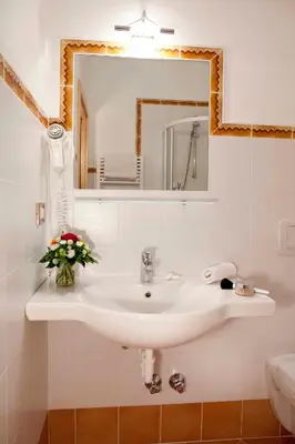 a bathroom with a white sink and a mirror at Hotel-Garni Appartement Gartenheim in Schenna