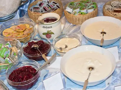 a table with bowls of jam and baskets of desserts at Hotel-Garni Appartement Gartenheim in Schenna