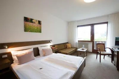a hotel room with a bed and a living room at Pension Sankt Urban in Merano