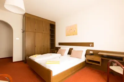 a bedroom with a large bed and a desk at Pension Sankt Urban in Merano