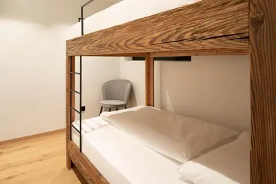 a bedroom with a bunk bed with a chair at LUXE VISTA Mountain Chalet Cermis - mitten auf der Alm und Skipiste in Cavalese