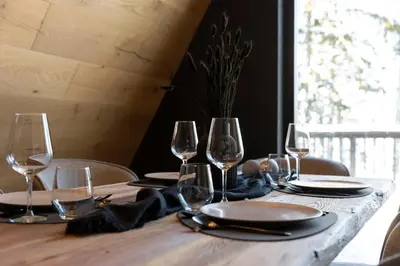 a wooden table with wine glasses and plates on it at LUXE VISTA Mountain Chalet Cermis - mitten auf der Alm und Skipiste in Cavalese
