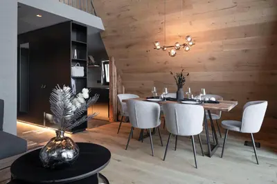 a dining room with a table and white chairs at LUXE VISTA Mountain Chalet Cermis - mitten auf der Alm und Skipiste in Cavalese