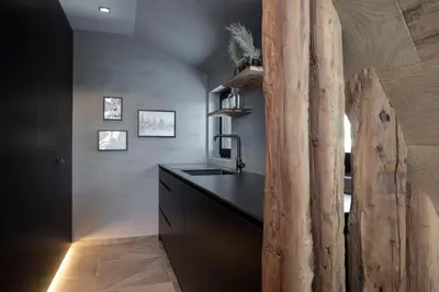 a kitchen with a sink and a wooden log wall at LUXE VISTA Mountain Chalet Cermis - mitten auf der Alm und Skipiste in Cavalese