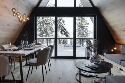 a dining room with a table and chairs and windows at LUXE VISTA Mountain Chalet Cermis - mitten auf der Alm und Skipiste in Cavalese