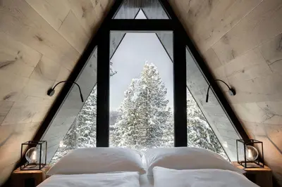 a bed in a room with a large window at LUXE VISTA Mountain Chalet Cermis - mitten auf der Alm und Skipiste in Cavalese