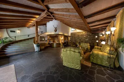a living room with a staircase and a couch and chairs at PALMENGARTEN Hotel Gstör in Lagundo