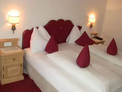 a bedroom with two beds with red and white pillows at PALMENGARTEN Hotel Gstör in Lagundo