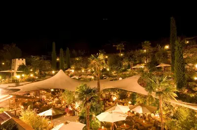a night view of a market with tents and palm trees at PALMENGARTEN Hotel Gstör in Lagundo