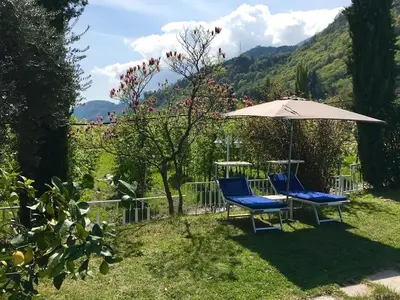 a couch sitting under a red umbrella on a patio at Garni Hotel Burgleitenhof in Lana