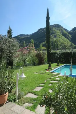 a patio with tables and chairs and an umbrella at Garni Hotel Burgleitenhof in Lana