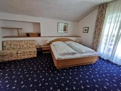 a bedroom with a bed and a desk and a couch at Garni Hotel Burgleitenhof in Lana