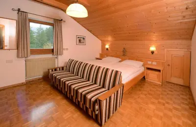 a bedroom with a bed and a couch in it at Apartment Puciacia - Bauernhof in Santa Cristina in Val Gardena