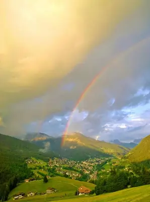 a rainbow in the sky over a green valley at Apartment Puciacia - Bauernhof in Santa Cristina in Val Gardena