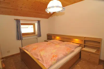 a bedroom with a bed and a window and a chandelier at Fiziderhof in Castelrotto