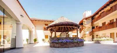 a fountain in the middle of a building with flowers at Aparthotel Kastel Seiser Alm in Castelrotto