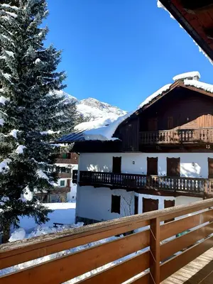 a house in the snow with a fence and a tree at luminoso ed accogliente, centralissimo appartamento indipendente in Cortina dʼAmpezzo