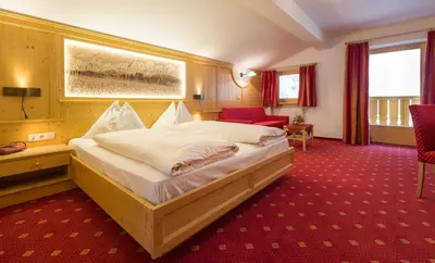 a bedroom with a large bed and a red carpet at Aktiv Hotel Schönwald in Nova Levante