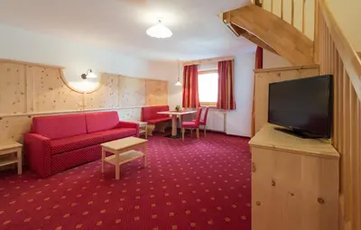 a living room with a red couch and a flat screen tv at Aktiv Hotel Schönwald in Nova Levante