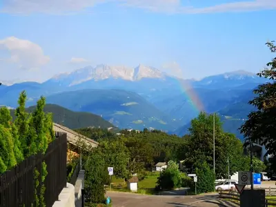 a rainbow over a mountain range with a street at Sonnenparadies in San Genesio Atesino