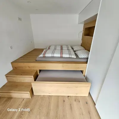 two beds in a small room with wooden floors at Sonnenparadies in San Genesio Atesino