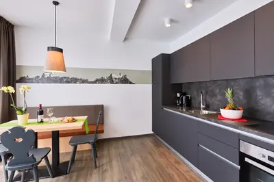 a kitchen with black and white cabinets and a wooden table at Residence Laitacherhof - Modern Apartments with Sauna in Chiusa