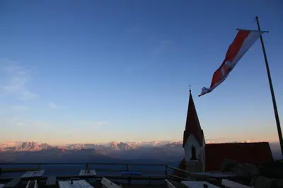 a flag on top of a church with mountains in the background at Residence Laitacherhof - Modern Apartments with Sauna in Chiusa